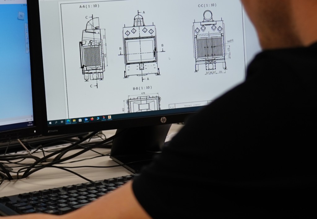 Gedetailleerde technische CAD-tekening van een Defro verwarmingsketel op een monitor, gezien over de schouder van een ontwerper